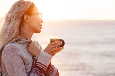 Kadın dışarıda çay içiyor.