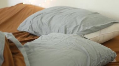 Buruşuk yatak, gri yastıklar, kahverengi çarşaf.