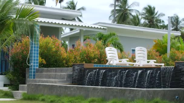 View of a tropical resort with a pool, an artificial waterfall — Stock Video