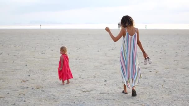 Mãe com duas filhas caminha ao longo da praia ao pôr do sol — Vídeo de Stock