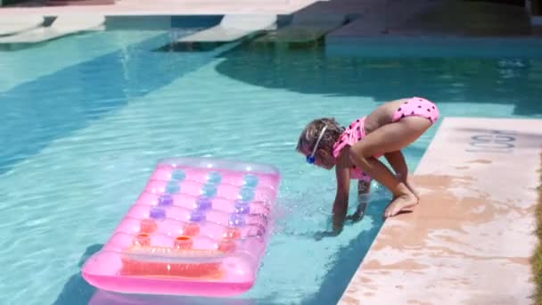 Niña de 7 años saltando sobre un colchón inflable en la piscina — Vídeos de Stock