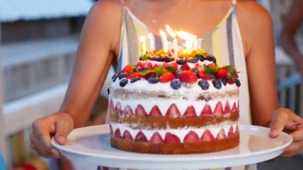 Молода жінка несе великий фруктовий торт зі свічками — стокове відео