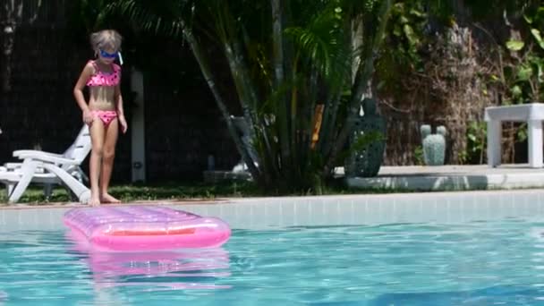 7 anos de idade menina pulando em um colchão inflável na piscina — Vídeo de Stock