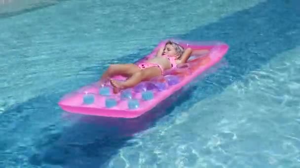Gadis pirang berenang di kolam renang di atas kasur karet. — Stok Video