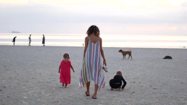 해 가질 때 두 딸 과 함께 해변을 따라 걷는 어머니 — 비디오