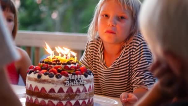 7 jaar oud meisje doet een wens en blaast de kaarsen op de taart — Stockvideo