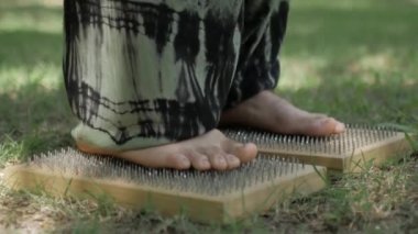Adam çivilerin üzerinde duruyor. Ayaklara yakın çekim