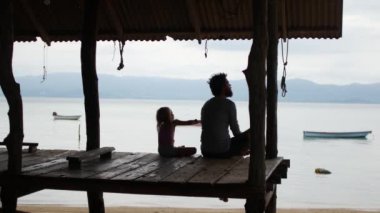 Baba ve kızı deniz kenarındaki köprüde oturuyorlar.