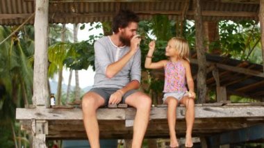 Baba ve kızı deniz kenarındaki köprüde oturuyorlar.