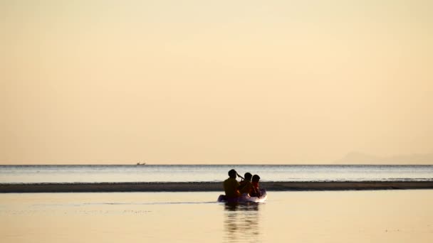 Solnedgång människor går längs stranden längs spottet längs de grunda — Stockvideo