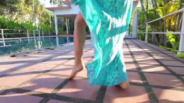 Dinamik ve estetik açıdan tatmin edici bir çekim, yüzme havuzunda zarif bir şekilde dans eden kısa saçlı kızın alt vücut ve kol hareketlerine odaklanır. Uçan mavi kimono elbisesi