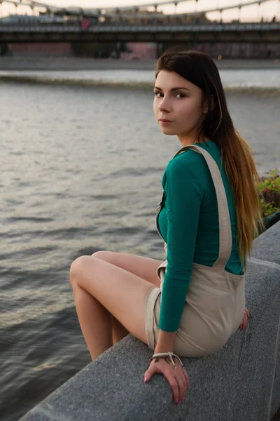 Ung kvinna sitter vid bron — Stockfoto