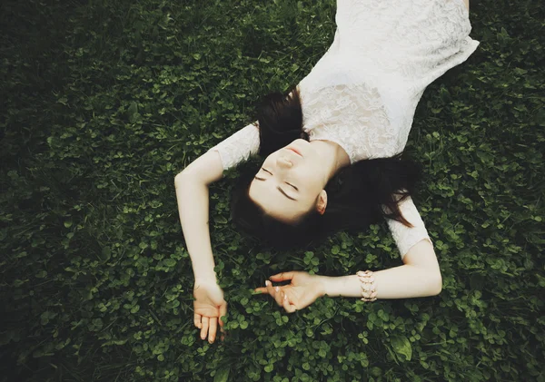 Jeune fille blanche en robe de soleil couché sur l'herbe verte dans le jardin — Photo