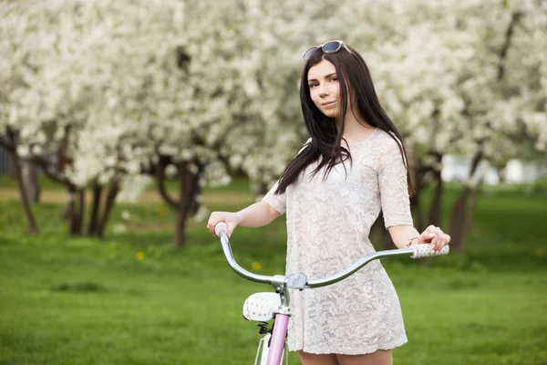 Chica joven en vestido de montar una bicicleta en el parque —  Fotos de Stock