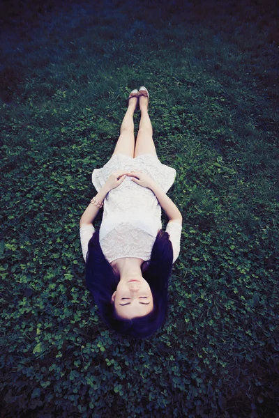 Jeune fille en robe de soleil couché sur l'herbe verte — Photo