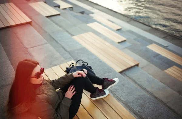 Jovem hipster menina em óculos de sol e parka sentado — Fotografia de Stock