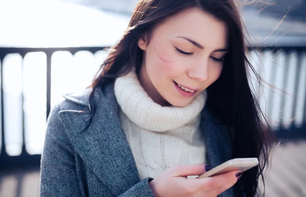 Pretty brunette using her touch screen smart phone — Stock Photo, Image