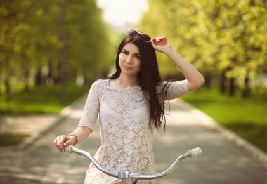 Genç esmer kız bir parkta bir bisiklet ile