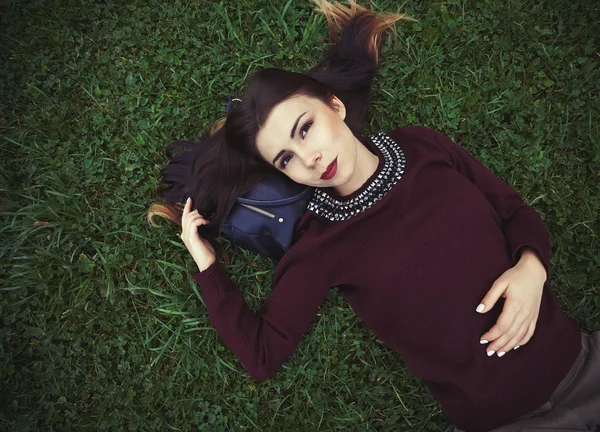 Young girl lying on green grass in park — Stock Photo, Image