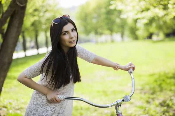 Fiatal nő sundress élvezi a kerékpár út a parkban — Stock Fotó