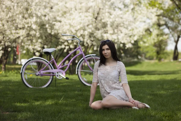 Young girl in sundress riding a bicycle in park — Stock Photo, Image