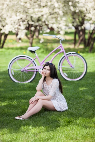 Jeune fille brune avec un vélo dans un parc — Photo