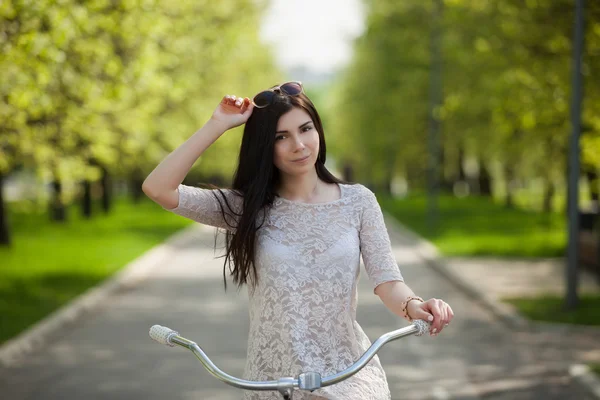 Giovane ragazza bianca con bicicletta nel parco primaverile — Foto Stock