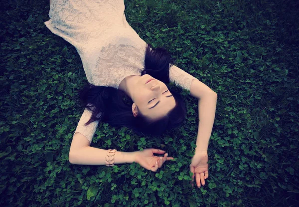 Jeune fille en robe de soleil couché sur l'herbe verte — Photo