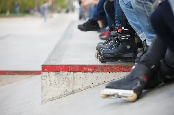 Agressivo inline rollerblader sentado no parque de skate ao ar livre — Fotografia de Stock