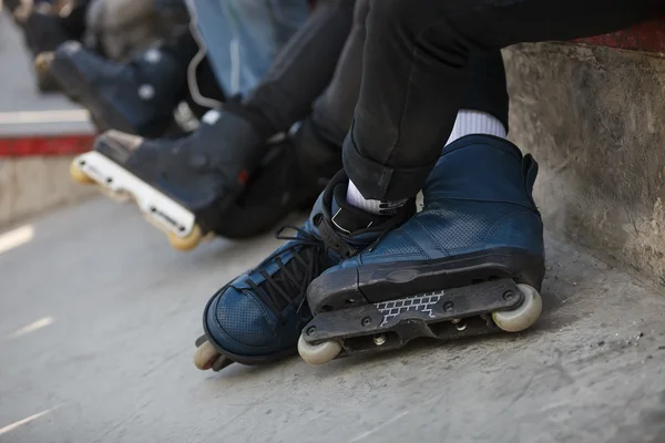 Agressivo inline rollerblader sentado no parque de skate ao ar livre — Fotografia de Stock