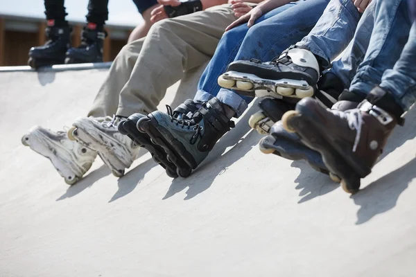 Agresivo patinador en línea sentado en la rampa en skatepark — Foto de Stock