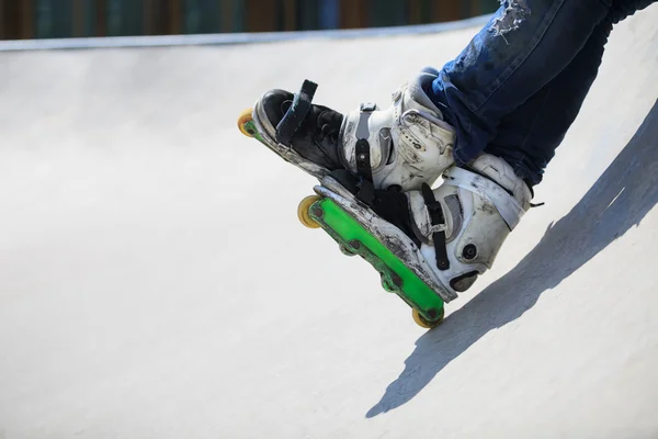 Agressivo inline rollerblader sentado na rampa no skatepark — Fotografia de Stock