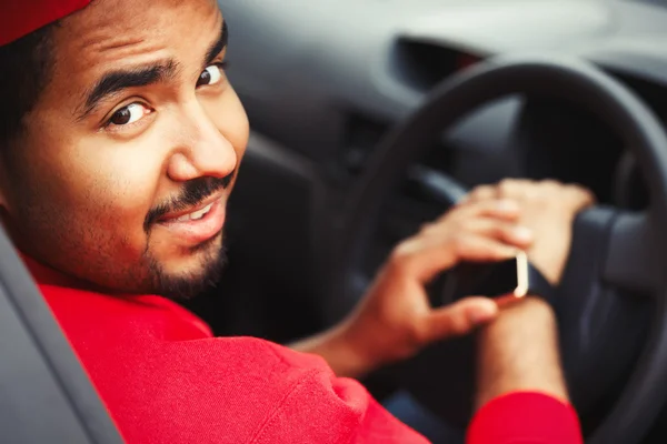 Black boy using smart wrist watches sitting in car — Stock Photo, Image