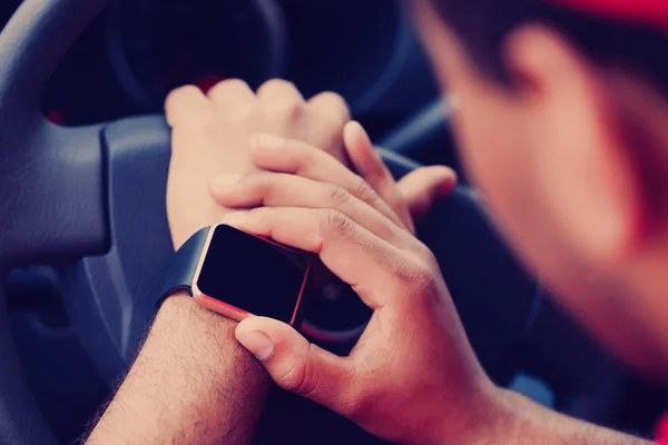 Black boy using smart wrist watches sitting in car