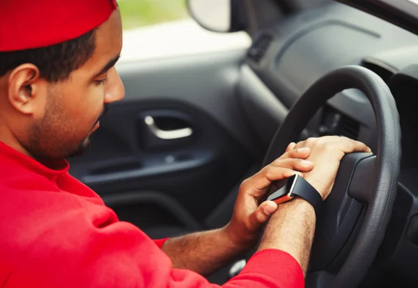 Black boy using smart wrist watches sitting in car — Stock Photo, Image