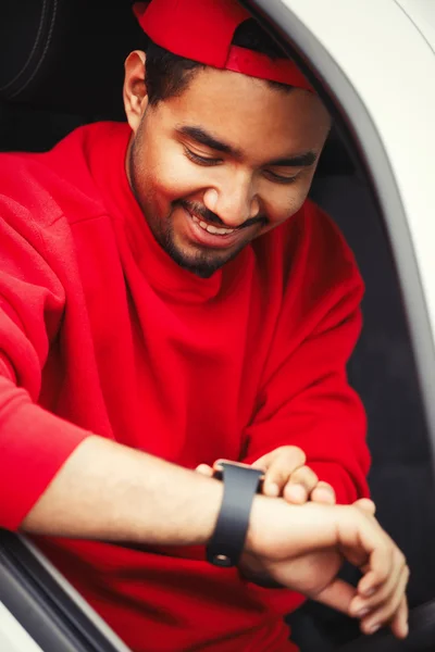 Black boy using smart wrist watches sitting in car — Stock Photo, Image