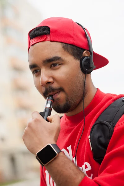 Hombre negro joven fumar dispositivo vaporizador de cigarrillos electrónicos — Foto de Stock