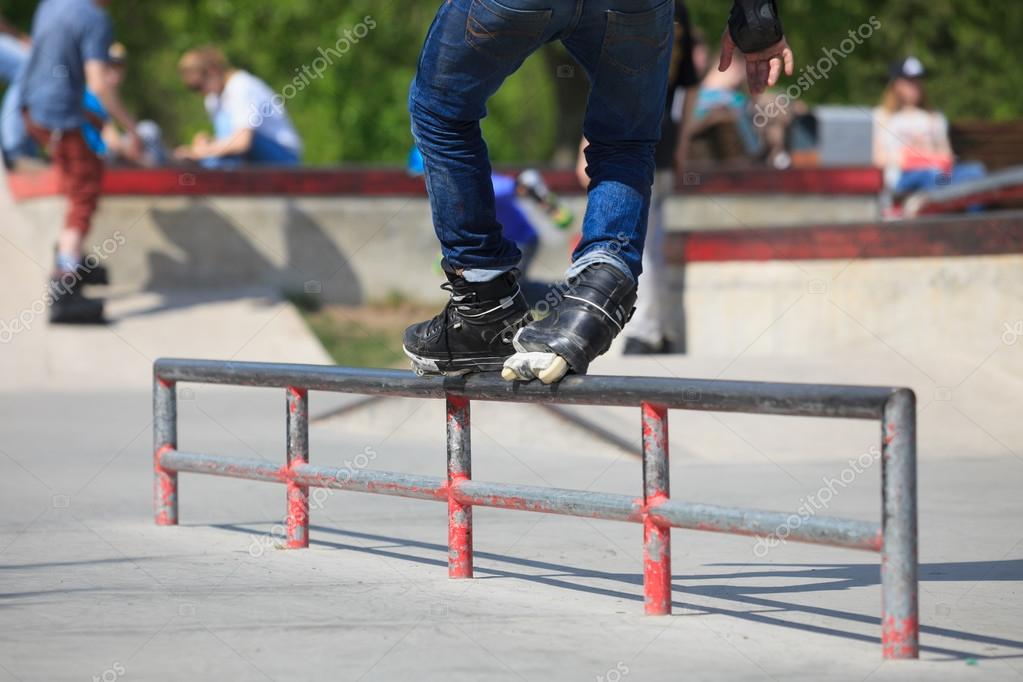 Aggressive inline rollerblader grinding on rail in skatepark Stock