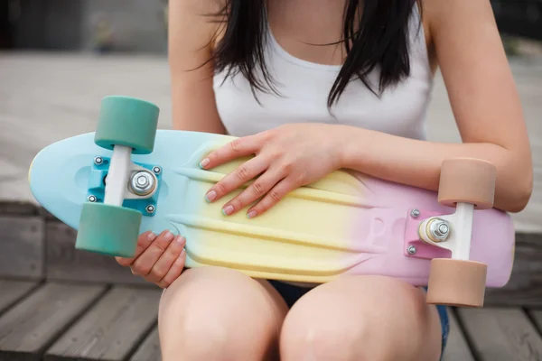 Ragazza tiene colorato breve cruiser skateboard ponte — Foto Stock