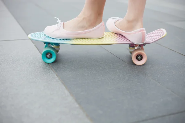 Feet of girl riding colorful short cruiser skateboard — Stock Photo, Image