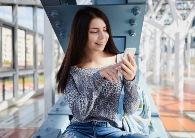 Büyük gümüş modern akıllı telefon kullanan esmer genç kız 