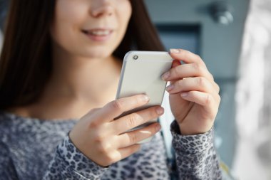 Büyük gümüş modern akıllı telefon kullanan esmer genç kız 