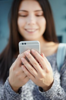 Modern çift kameralı akıllı telefon kullanarak gülümseyen genç kız