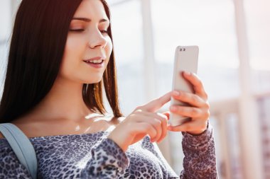 Modern çift kameralı akıllı telefon kullanarak gülümseyen genç kız