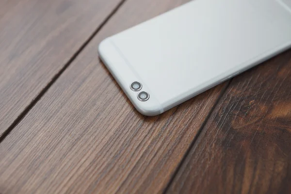 Современный смартфон с двумя задними камерами на деревянной поверхности — стоковое фото