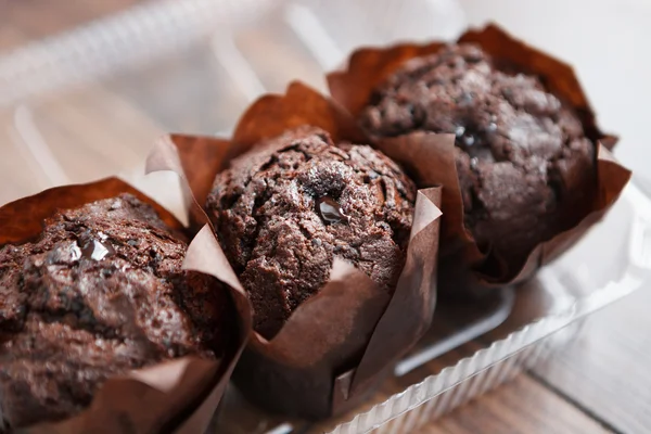 Three chocolate muffins in plastic container