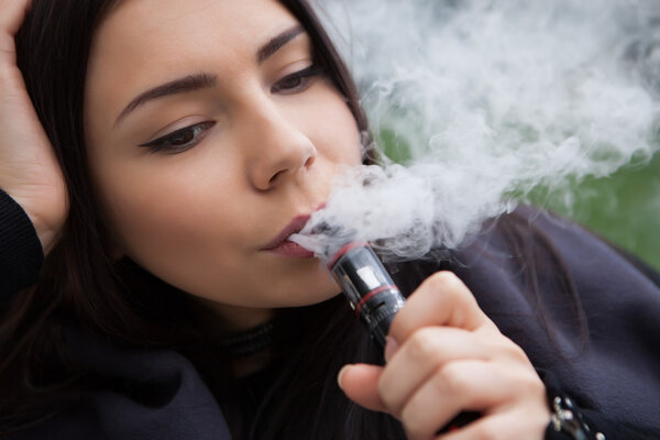 Young girl vaping e-cig vaporizer device