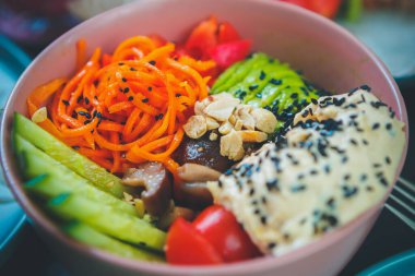 Asya restoranında öğle yemeği için lezzetli poke kasesi servis edilir. Geleneksel Hawaii mutfağı. Taze avokado, salatalık, humus, Kore havucu ve mantarları ile birlikte vegan kafede seramik tabakta servis edilir.