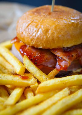 Fast food kafe menülerinde altın patates kızartması ile servis edilen domates ketçap soslu lezzetli hamburger. Restoran yemeği yakın. Kızarmış hamburger.