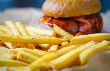 Fast food kafe menülerinde altın patates kızartması ile servis edilen domates ketçap soslu lezzetli hamburger. Restoran yemeği yakın. Kızarmış hamburger.